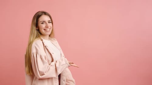 Smiling Woman Gesturing on Pink Background