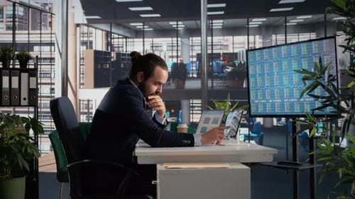 Man Analyzing Data on Laptop in Office
