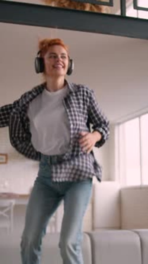 Woman With Headphones Dancing on Couch at Home