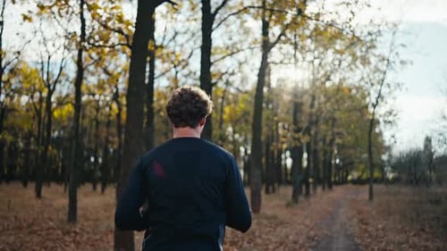 Rear View of a Brunette Man with a Black Sports Uniform with Curly Hair and a Beard Runs Along an