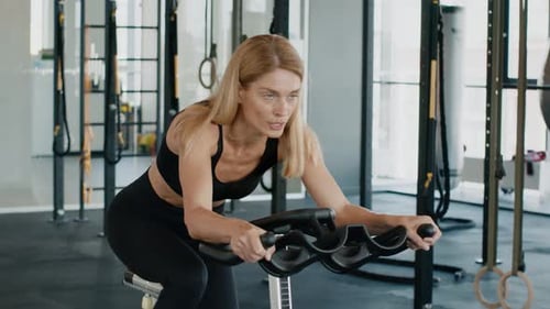Woman Working Out on Stationary Bike in Gym