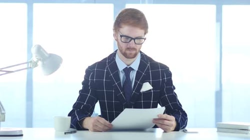 Man Reading Office Douments at Work Red Hairs