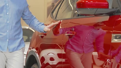 Man Exploring a Sleek New Automobile at a Vibrant Car Dealership