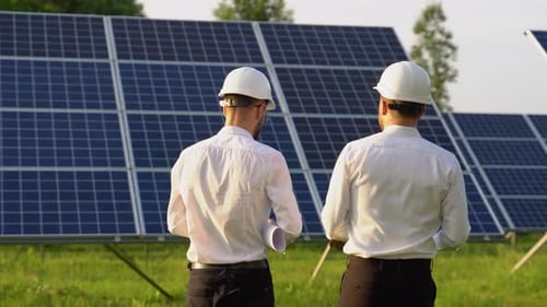 Zwei Ingenieure gehen und untersuchen das Konzept alternativer Energien und ihre Auswirkungen auf Photovoltaik-Solarmodule
