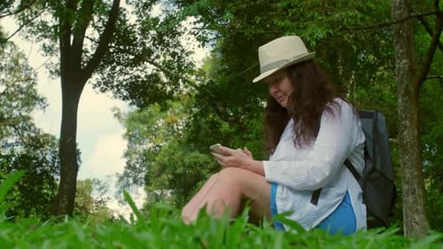 Tourist Using Smartphone Sitting on Grass in a Park