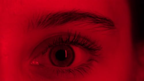 Girl'S Large Blinking Eye In Red Light Close Up View