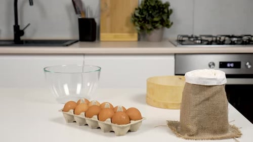 Slow Motion Whole Raw Hen Eggs Being Near Glass Bowl Holding Plain White Flour on Kitchen Table