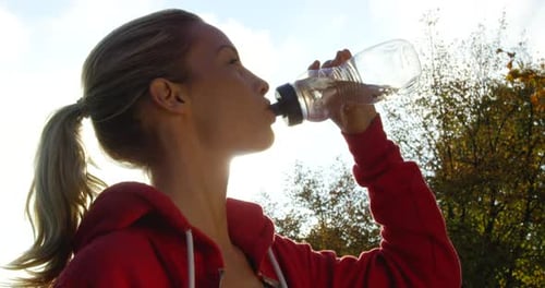 Woman Drinking Water Outdoors in Sunlight