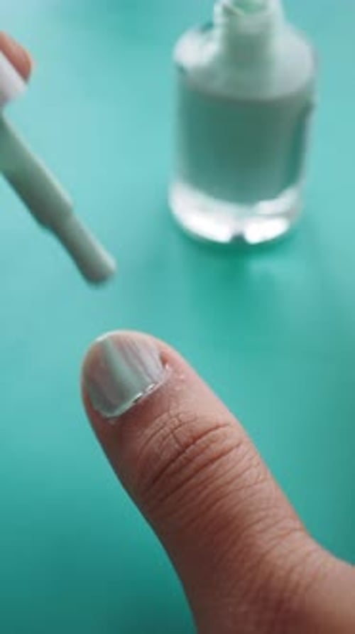 Applying Light Blue Nail Polish Close Up