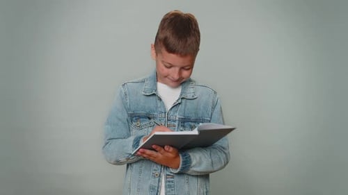 Boy Writing in Notebook with Pen Indoors