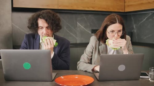 Colleagues Husband and Wife Enjoying Sandwiches at Work Lunch Together in Home Office Combining Food