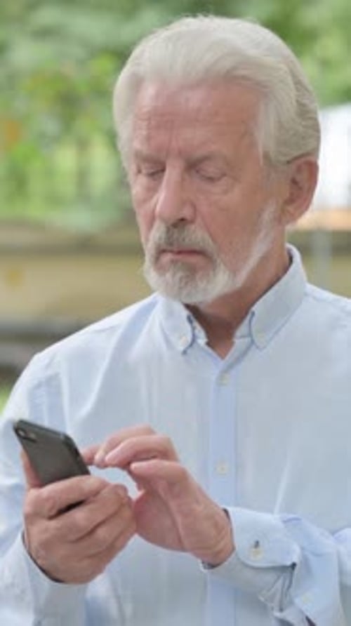 Senior Man Using Smartphone Outdoors in Vertical Video