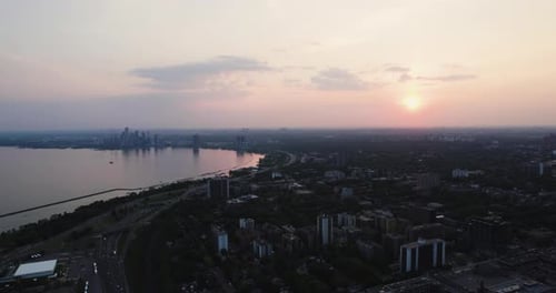 Aerial view backwards over the Parkdale district and Lake Ontario, sunset in Toronto, Canada