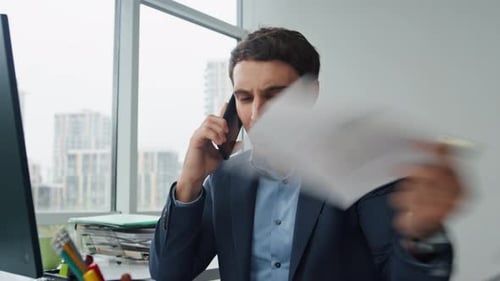Stressed Businessman Talking on Phone in Office