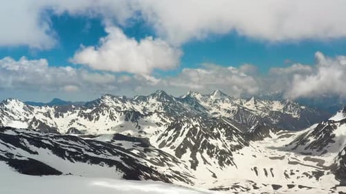 Air flight through mountain clouds over beautiful snow-capped peaks of mountains and glaciers.