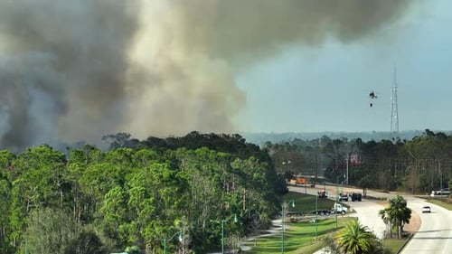 Aerial View of Fire Department Helicopter and Firetrucks Extinguishing Wildfire Burning Severely in