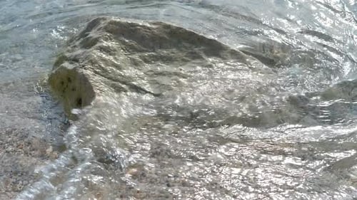 Gentle Waves Washing Over Coastal Rock on Sandy Beach