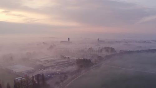 Aerial view of foggy sunrise over church and fields, Netherlands.