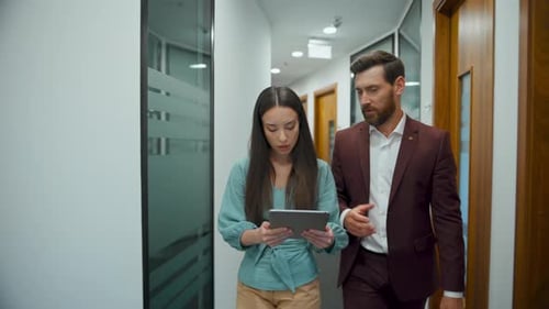 Creative team colleagues discussing business on a tablet in modern office space