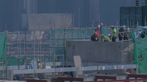 Builders On The Roof Of A High Rise Building Under Construction In Hong Kong
