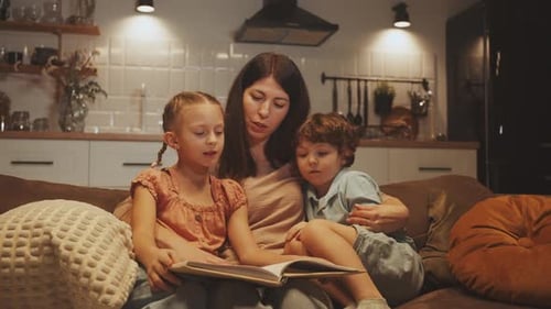 Woman Reading Book to Children on Couch Indoors