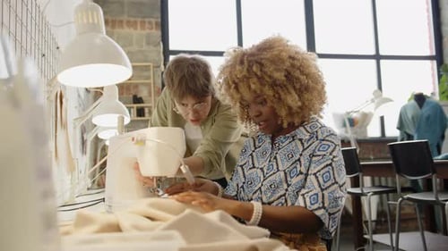 Two Women Sewing Fabric Together at Sewing Machine