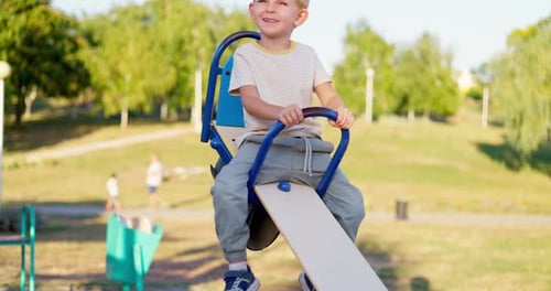 Little Boy Laughing and Having Fun Swinging on Seesaw Board Playing Playground