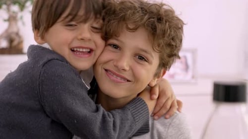 Two Happy Boys Hugging Indoors Smiling