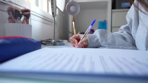Close-up of a girl writing in a notebook with a pen in hand. Static