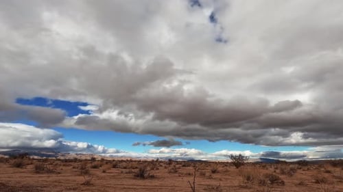 Clouds moving across the sky over the Mojave Desert's arid landscape on an overcast day - static wid