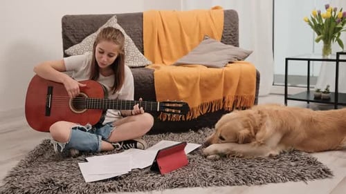 Teenage Girl Plays Guitar with Dog in Living Room