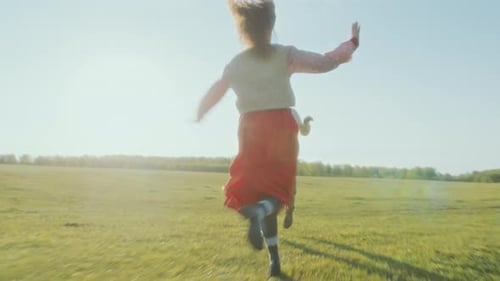 Cheerful Couple Running through Green Sunlit Meadow