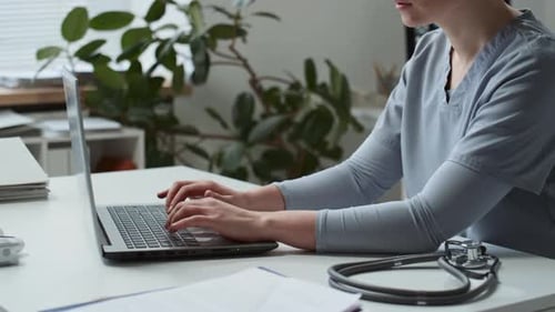 Healthcare Professional Works on Laptop in Medical Office