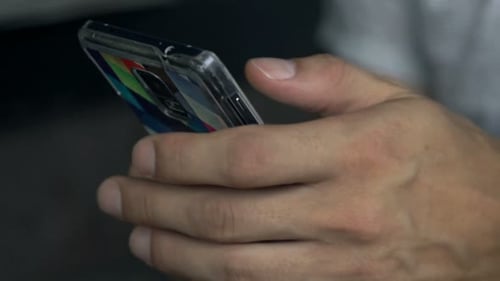 Man Browsing Internet on Smartphone and Drinking Beverage in Cafe 30s