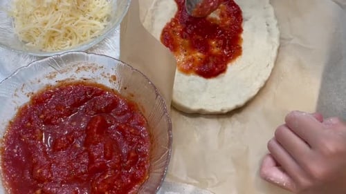Pizza! Child spreading tomato sauce on the dough. Home cooking with kids.