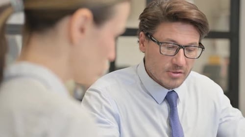 Businessman Talking with Businesswoman in Office