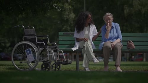 Young Woman Talking with Senior on Park Bench