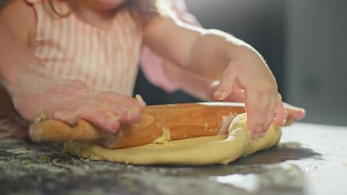 A Mother Teaches Her Little Daughter to Roll Out the Dough for Baking