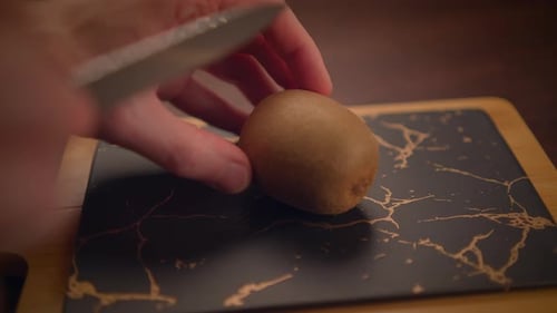 Kiwi is Cut in Half on Cutting Board