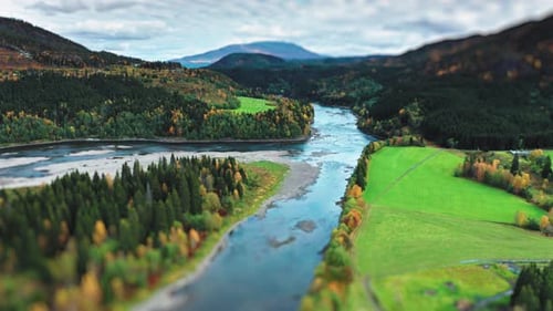 The aerial view of the scenic river cutting through farm fields and forests, framed by early autumn