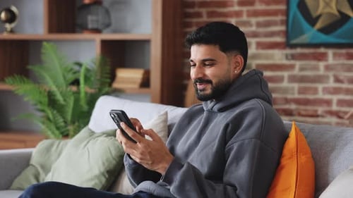 Man Using Smartphone Device Relaxing on Couch at Home