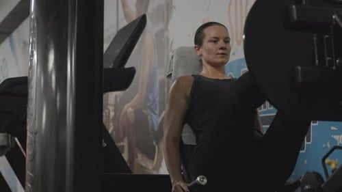 Woman Exercising on Leg Press Machine in Gym