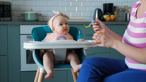 Baby Eating Food in High Chair at Home