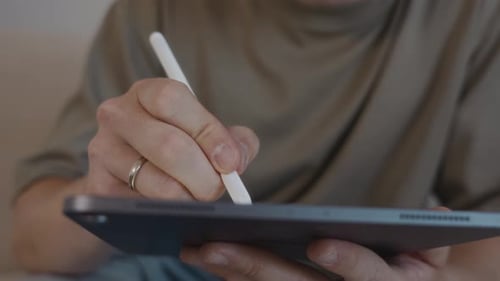 Adult man uses stylus on tablet device