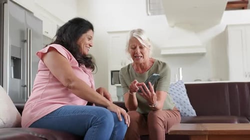 Women Chatting on Couch While Looking at Phone