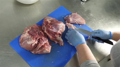 Gloved Butcher Cuts Meat for Food Preparation