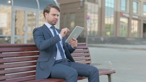 Businessman using Tablet while Sitting Outdoor on Bench