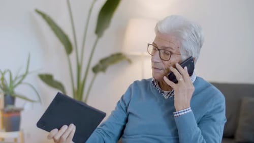 Senior Man Talking on Phone While Holding Tablet