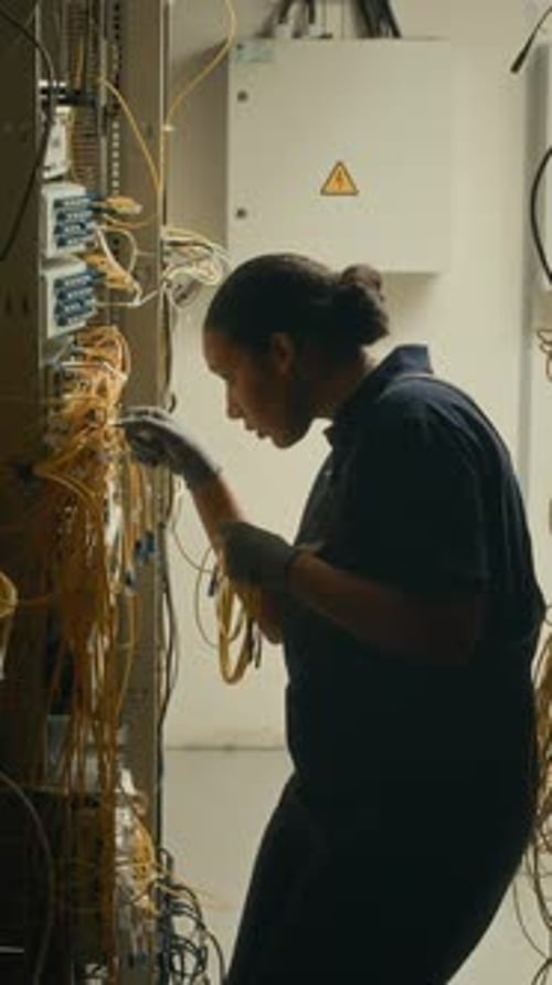 Technician Working on Cables in Server Room