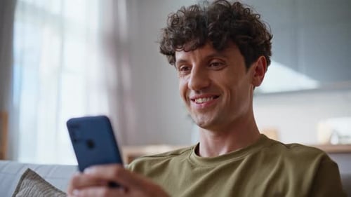 Young Adult Using Mobile Phone on Couch at Home